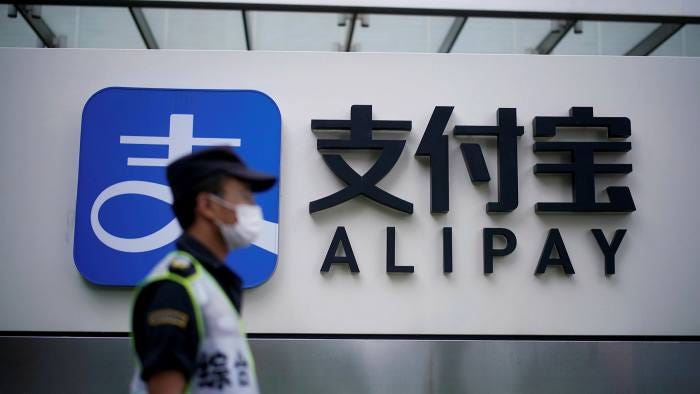 A security guard wearing a mask walks past an Alipay logo at the Shanghai office of Alipay, owned by Ant Group
