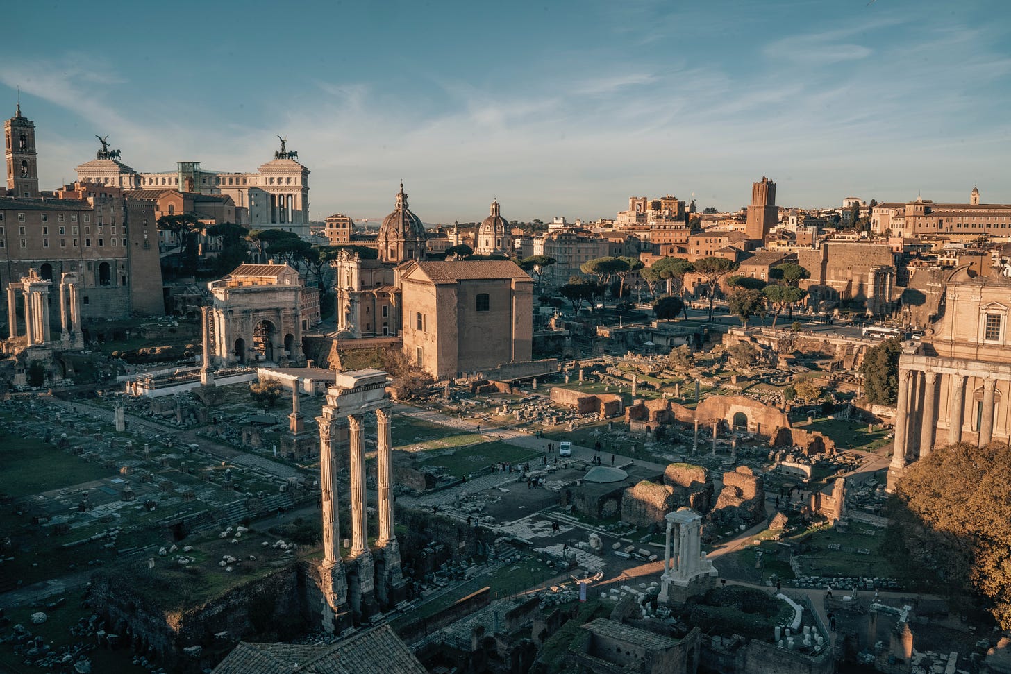 A panorama of ruined buildings in the Roman Forum against a blue and white sky