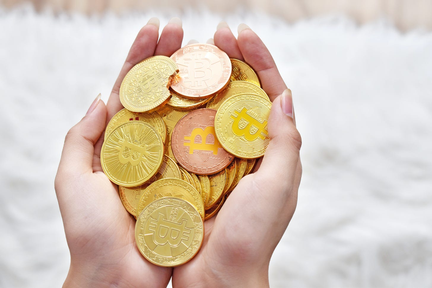 Novelty Bitcoin tokens held in a hand. Via Unsplash