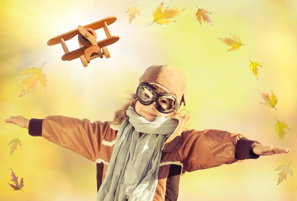 Girl arms out in span with falling leaves and wooden airplane