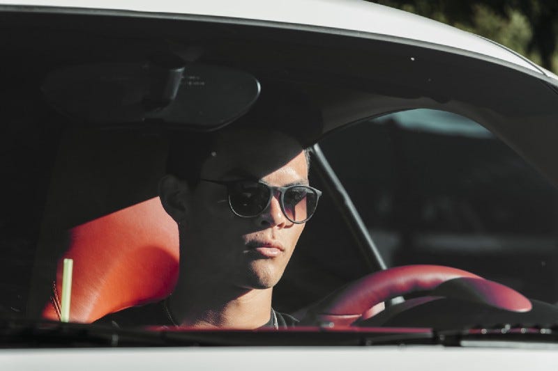 A driver wearing sun glasses and looking very serious