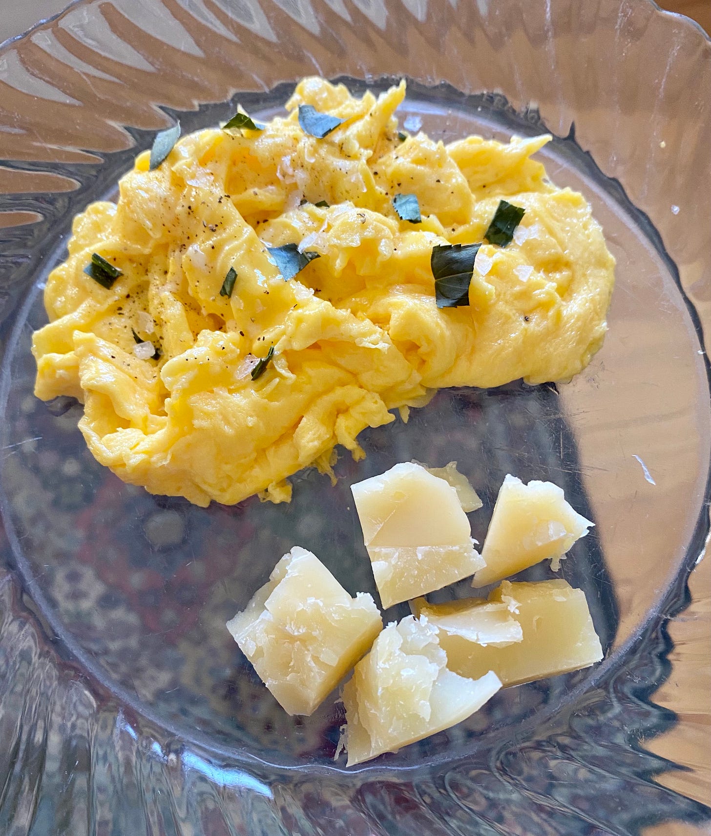 scrambled eggs and aged manchego chunks on a clear plate