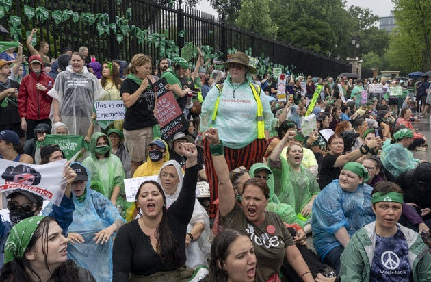 Abortion-rights protesters shout slogans after tying green flags to the fence of the White House.