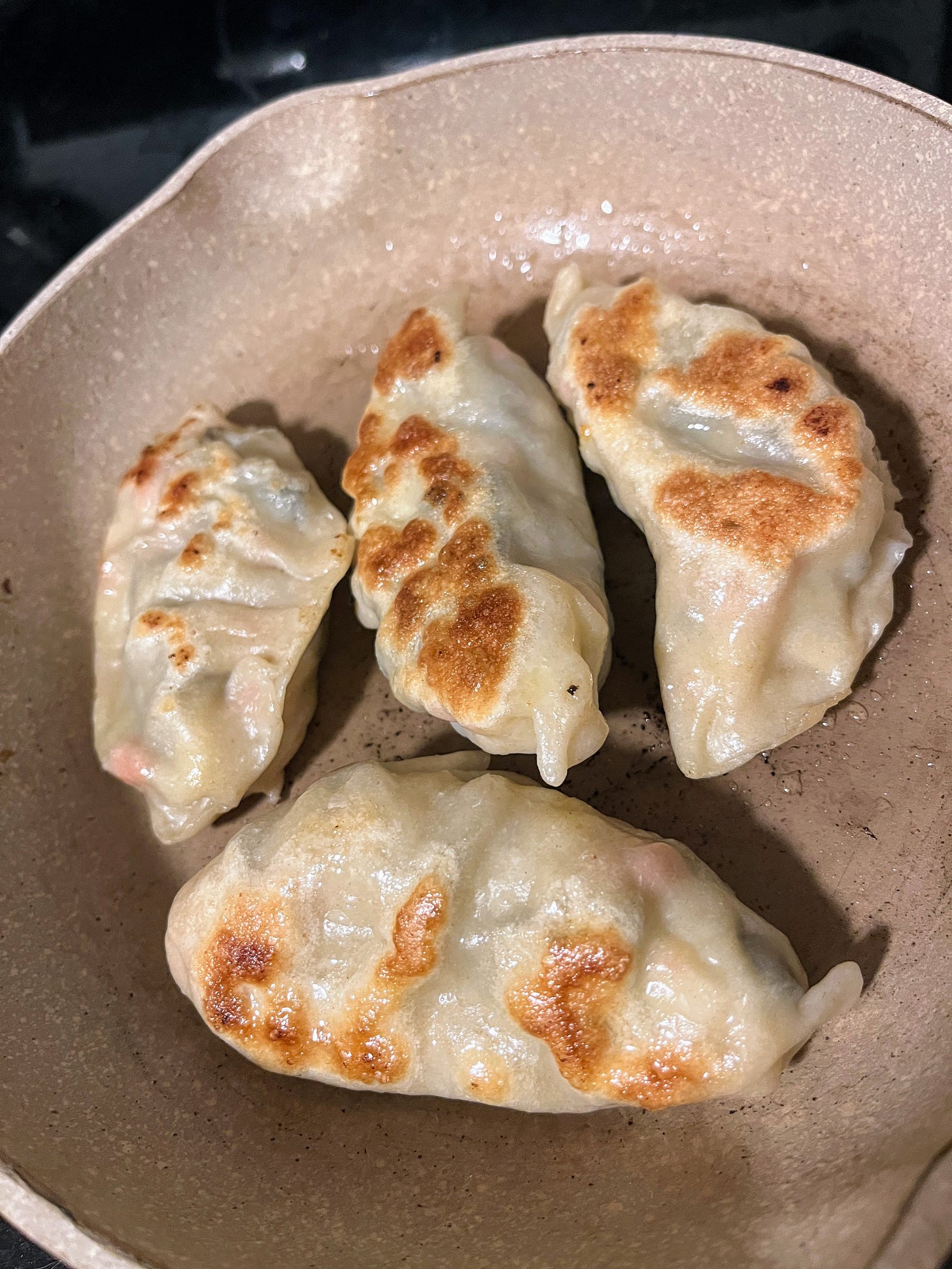 four potstickers in a gray frying pan