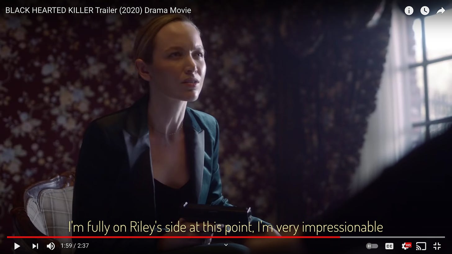 Vera/Riley wearing a forest green satin suit with black lapels, holding a handgun, sitting in a wing chair in a room with dark red floral wallpaper. She looks great! Captioned "I'm fully on Riley's side at this point, I'm very impressionable"