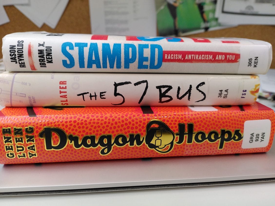 Stack of book spines, Stamped by Jason Reynolds & I. Kendi, The 57 Bus by Slater, Dragon Hoops by G. Yang