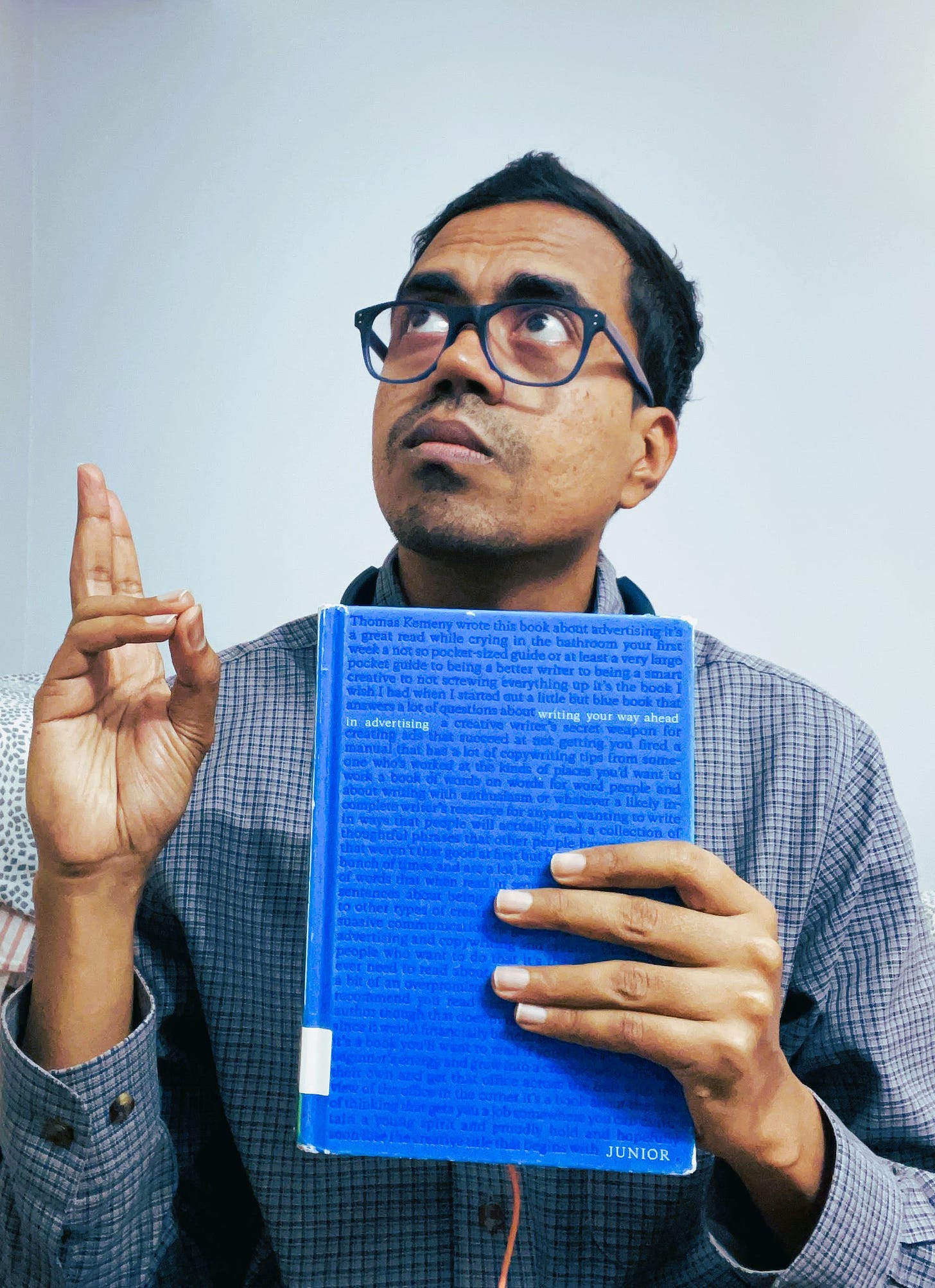 Nikhil Rajagopalan holding a copy of Junior by Thomas Kemeny and posing like a saint from renaissance times