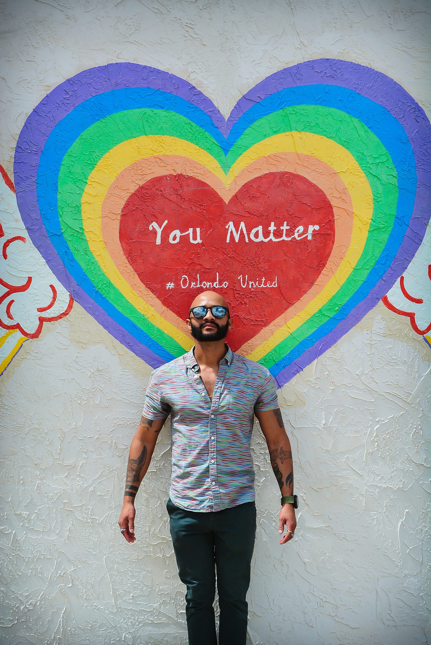 Jonattan standing in front of a #OrlandoUnited mural