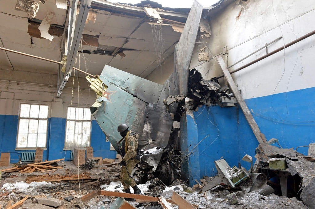 A member of the Ukrainian Territorial Defence Forces walks near remains of the Russian Sukhoi Su-25 assault aircraft