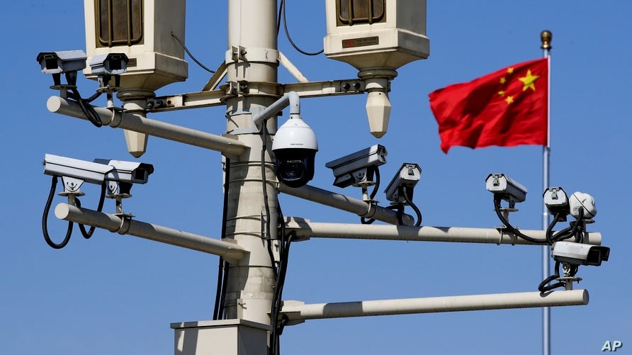 FILE - A Chinese national flag flutters near surveillance cameras mounted on a lamp post in Tiananmen Square in Beijing, China, March 15, 2019. 