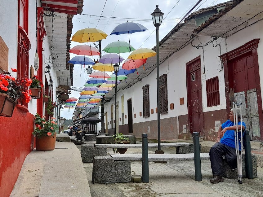I took this photo of the Spanish colonial street in Santo Domingo that had been dedicated to Carrasquilla, with a "roof" of umbrellas and plaques with quotes all along the walls. My friend, Don Ifrio, sits in repose, enjoying the view, his arm propped on his crutches.