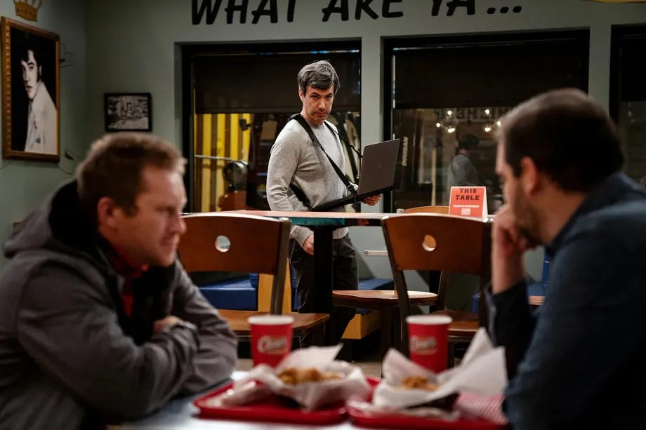 In a chicken restaurant, Nathan Fielder watching a rehearsal with Patrick (on the left).