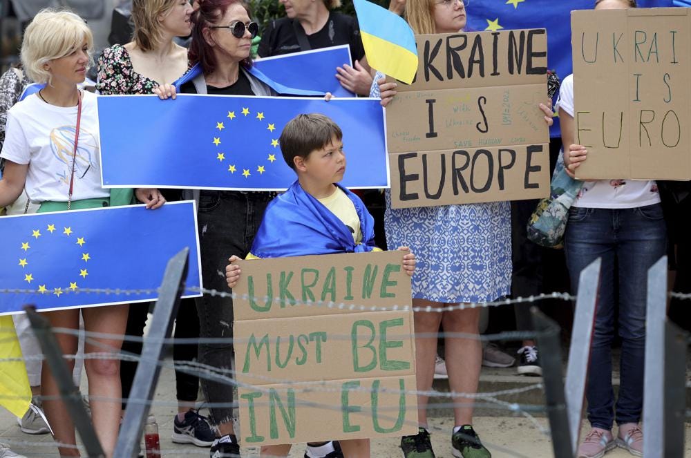 Protestors in support of Ukraine stand with signs and EU flags during a demonstration outside of an EU summit in Brussels, Thursday, June 23, 2022. European Union leaders are expected to approve Thursday a proposal to grant Ukraine a EU candidate status, a first step on the long toward membership. (AP Photo/Olivier Matthys)