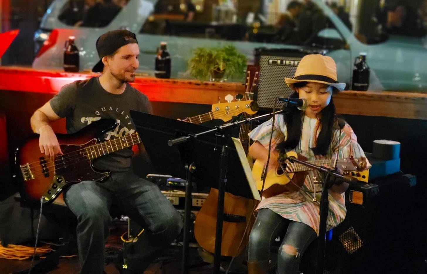 A man playing bass guitar and a young girl playing a ukelele