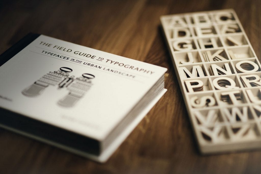book on typography on wooden table with box of wooden letters next to it