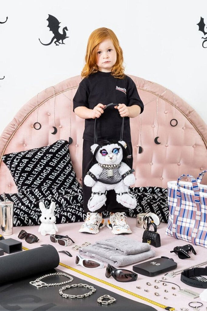 A young girl is pictured holding a teddy bear in bondage-style gear on the gift shop section of the Balenciaga website.  