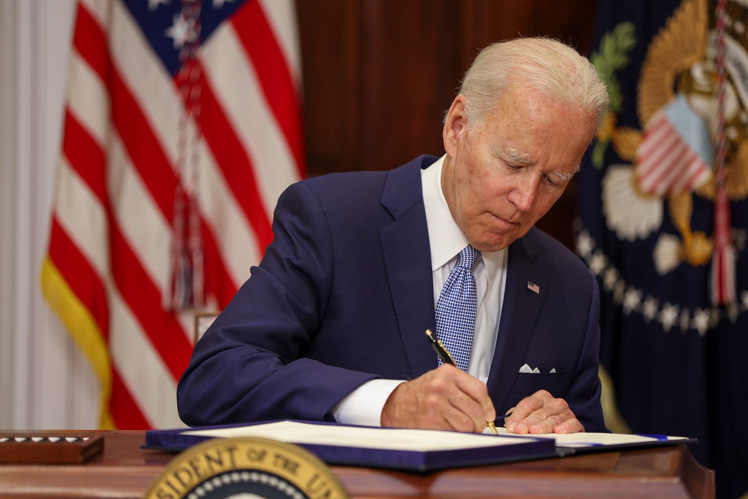 Joe Biden signs the Bipartisan Safer Communities Act on June 25, 2022. (Photo by Tasos Katopodis/Getty Images).