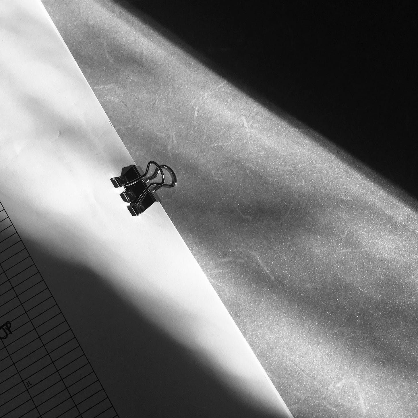 close up photo of a binder clip with a ray of light across the frame.
