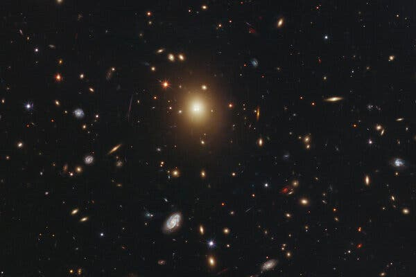 The galaxy cluster Abell 2261, captured by the Hubble Space Telescope. The brightest galaxy, center left, is about one million light-years across and about 10 times the diameter of the Milky Way.