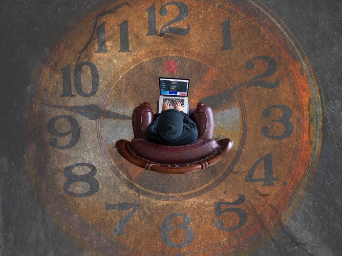 A man sitting in chair with a laptop in the middle of a clock painted into the ground.