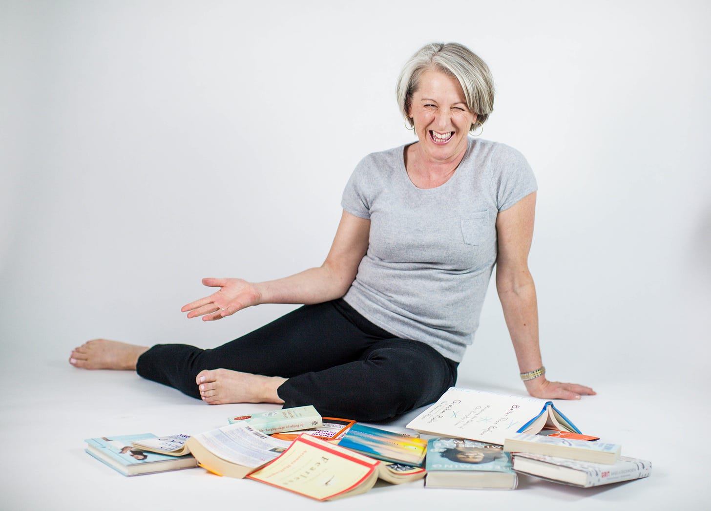Author Catherine Palmer laughing as she sits amidst a pile of self-help books