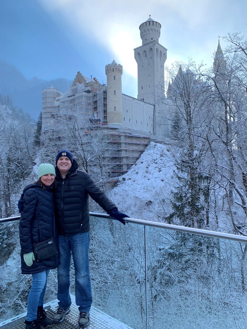 An exterior picture ofNeuschwanstein Castle with Gary and Lisa standing in front of it.