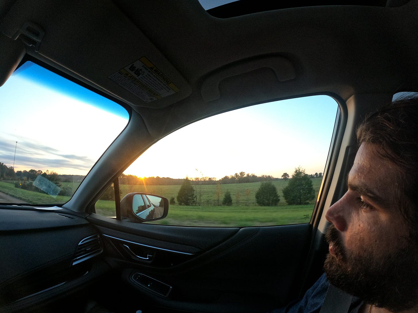 Anthony staring out the window as the sun sets over a green field in the Mississippi Delta