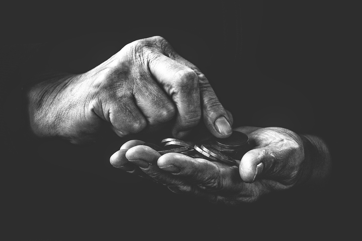 Black and white image of two male hands counting coins.