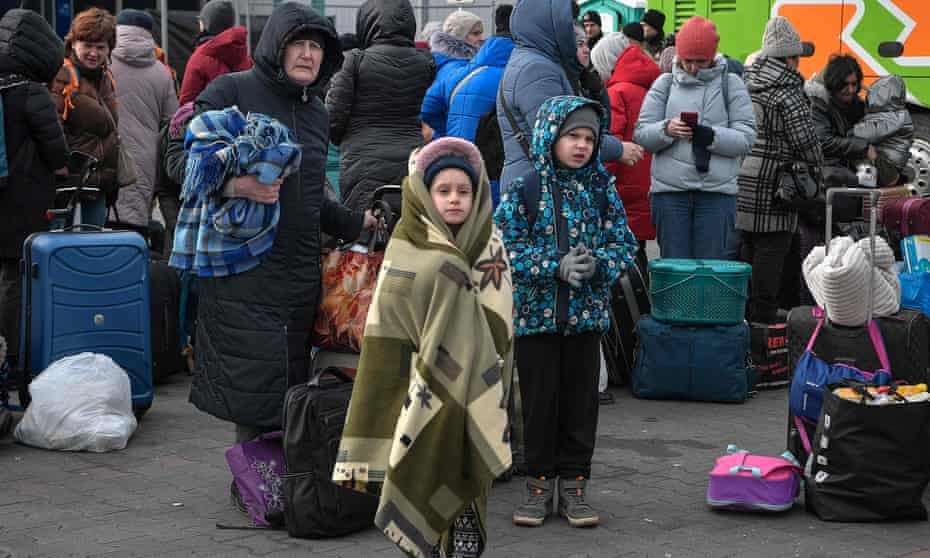 People fleeing the war in Ukraine stand with their luggage as they wait to board buses near the Polish city of Przemyśl.