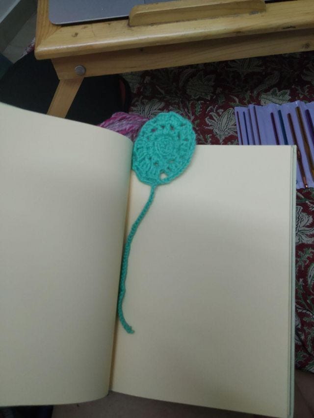 A book mark of a green spiral circle inside a book.