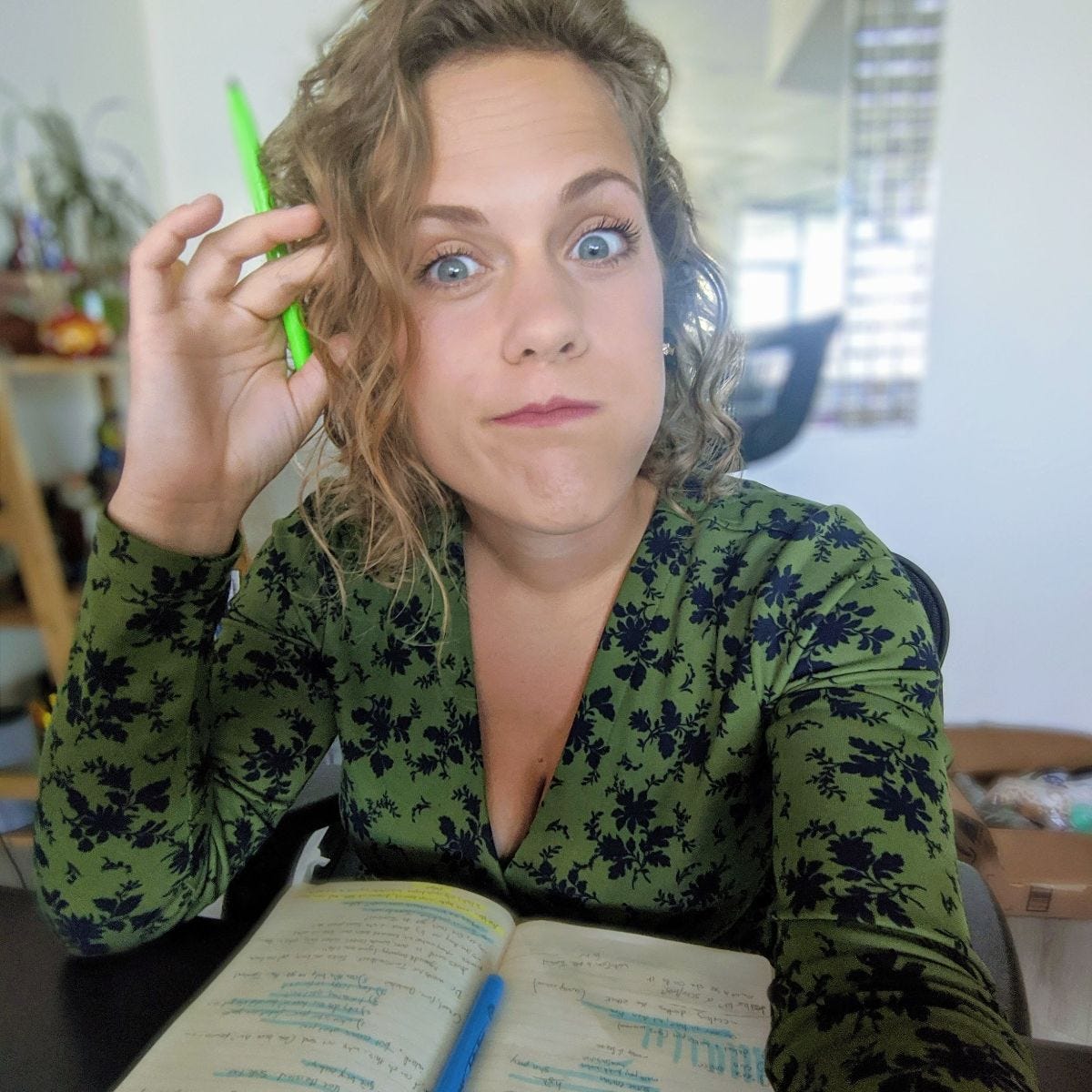 a white woman in a green wrap dress making a silly face and holding a green highlighter