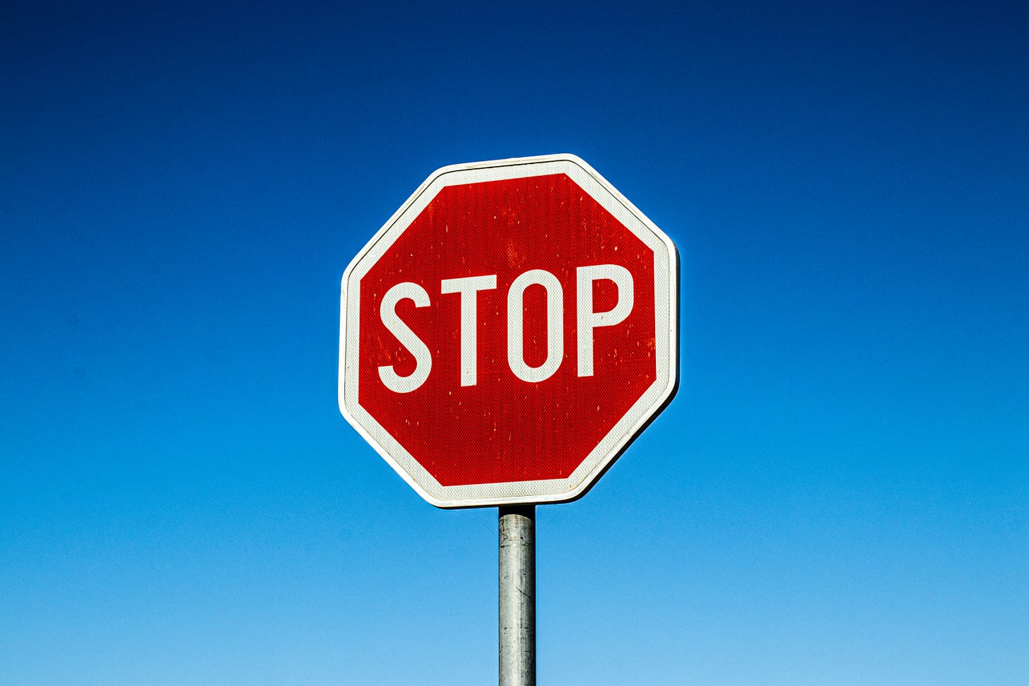 A red stop sign standing in front of a blue sky.