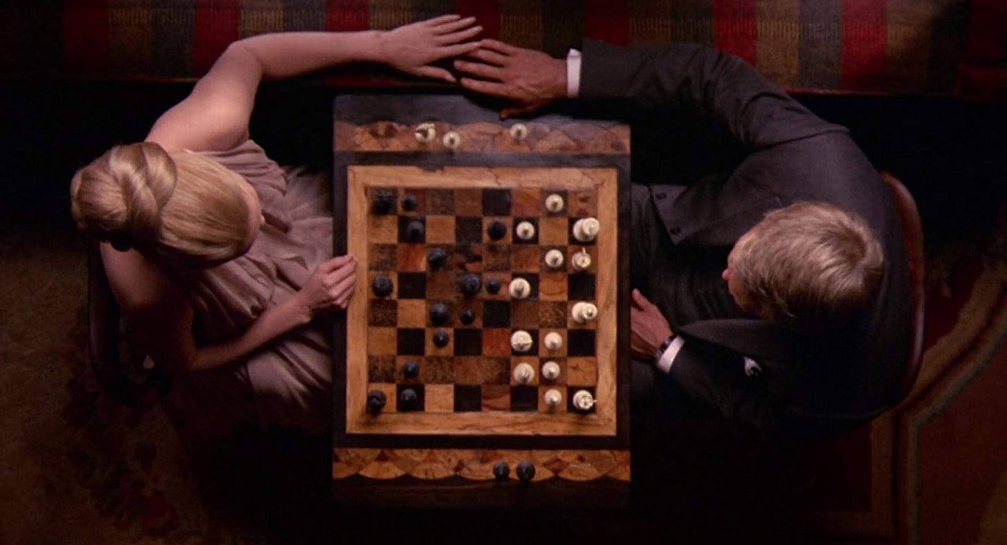 Top down shot of McQueen and Dunaway playing chess from the film