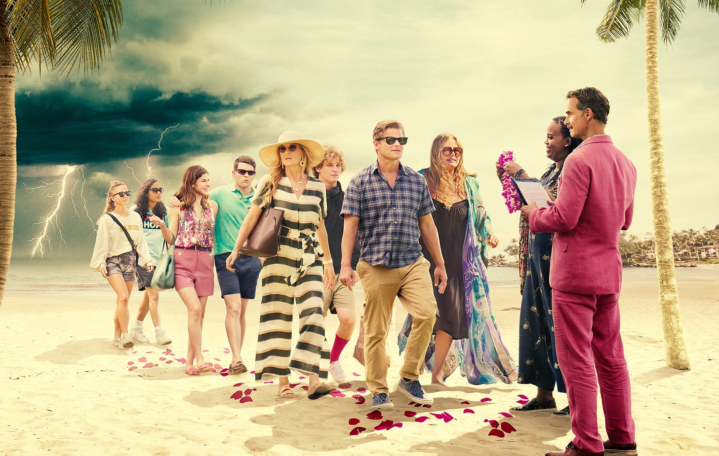 A group of tourists, mostly white, is greeted by two concierges in a Hawaiian setting