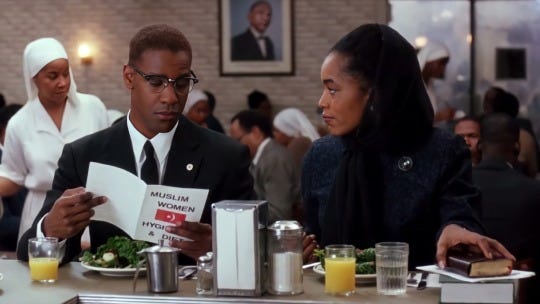 This image shows Malcolm X (played by Denzel Washington, left) having lunch with Betty Shabazz (played by Angela Bassett, right) in a Nation of Islam diner in one of Malcolm X's best scenes. This image shows Malcolm X (played by Denzel Washington, left) having lunch with Betty Shabazz (played by Angela Bassett, right) in a Nation of Islam diner in one of Malcolm X's best scenes.
