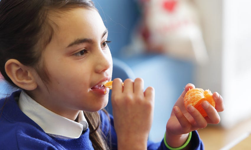 Young girl eating mandarin in school