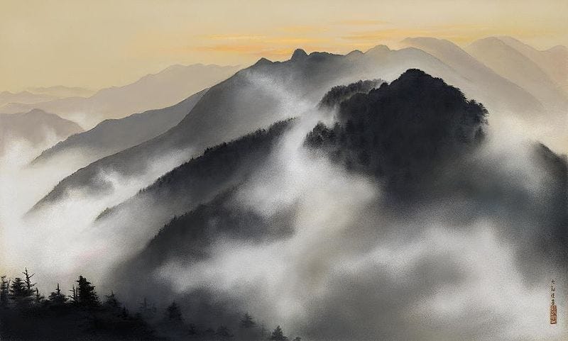 A range of densely forested mountains covered in mist