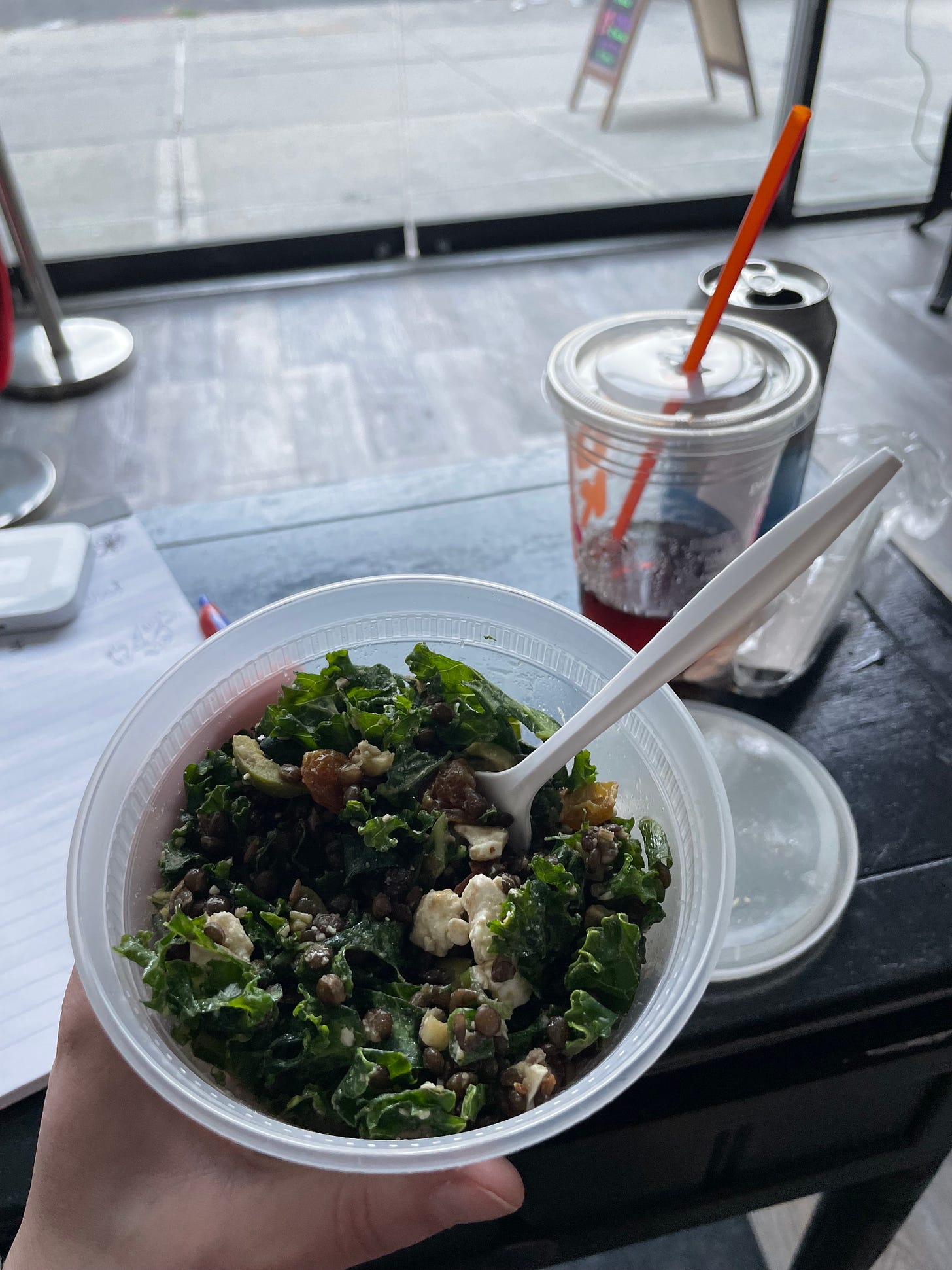 pint container of lentil salad at table with Dunkin cold brew in background