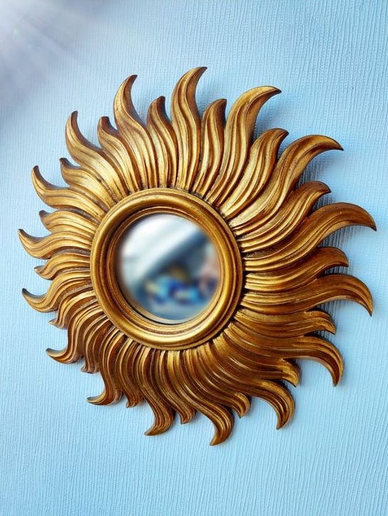 A small mirror with massive golden petals framing the mirror like the rays of the sun