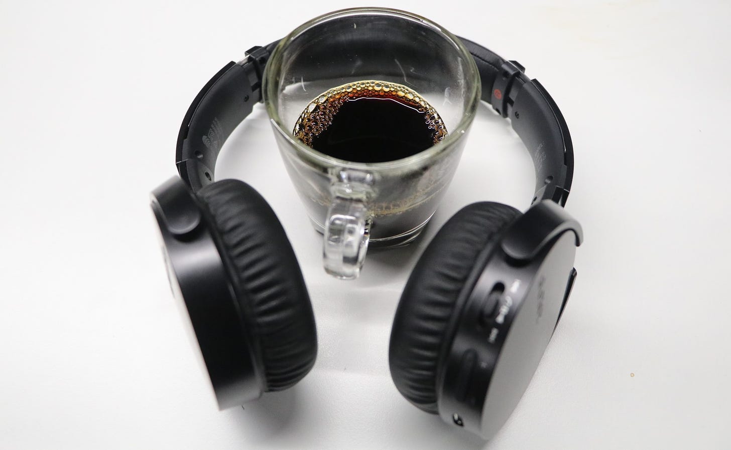 A cup of coffee inside a pair of over-ear headphones on a table