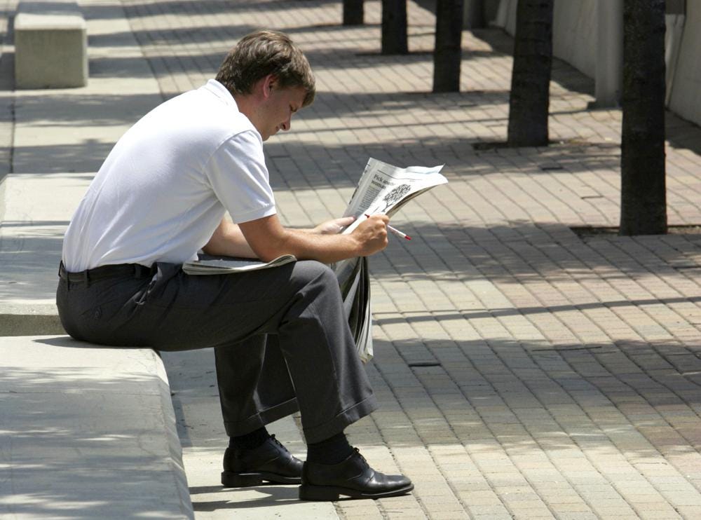 FILE - A man reads a newspaper during his lunch break in Cincinnati on July 6, 2005. A report from Northwestern University says local newspapers in the United States are dying at the rate of two per week. There has been growth in digital alternatives, but not nearly enough to compensate for what has been lost. (AP Photo/Al Behrman, File)