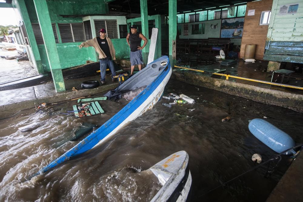 Fishermen look at boats partially submerged in water after Hurricane Julia swept through the area in Bluefields, Nicaragua, Sunday, Oct. 9, 2022. Hurricane Julia hit Nicaragua's central Caribbean coast and dumped torrential rains across Central America before reemerging over the Pacific as a tropical storm. (AP Photo/Inti Ocon)