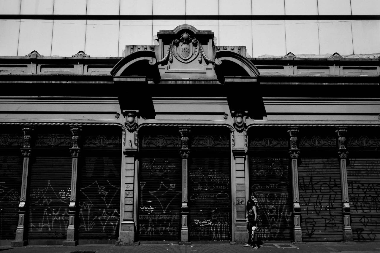Pórtico antigo no centro de São Paulo com portas de metal abaixadas, imagem em preto e branco.