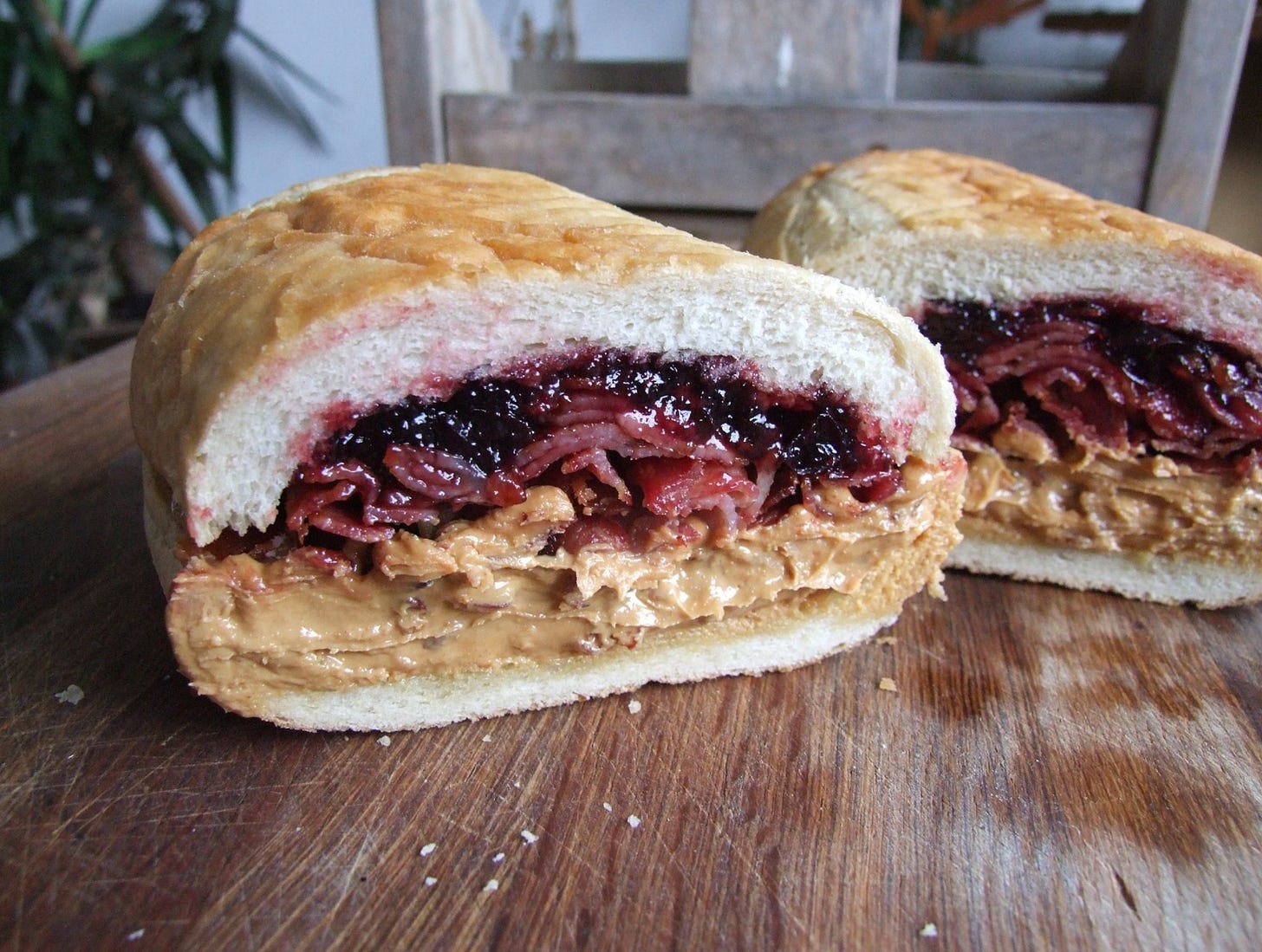 A cross section of big bread roll filled with grape jelly, peanut butter and bacon. 