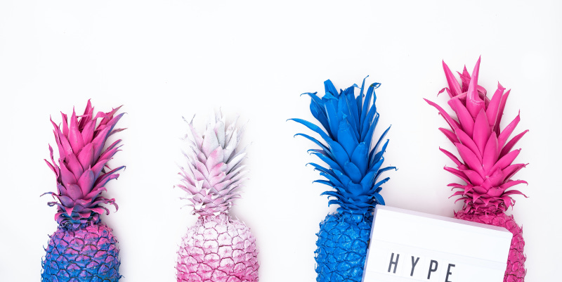 four colorful pineapples with a sign that reads "hype"