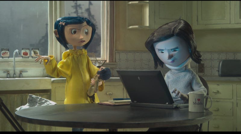 A still from the stop-motion movie Coraline. Coraline is standing next to the kitchen table while her mother stares at a computer screen, blue light reflecting on her face. 
