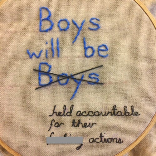 Picture of needlepoint with words "Boys will be held accountable for their [bleeping] actions" The second "boys" is crossed out in the phrase "Boys will be boys."