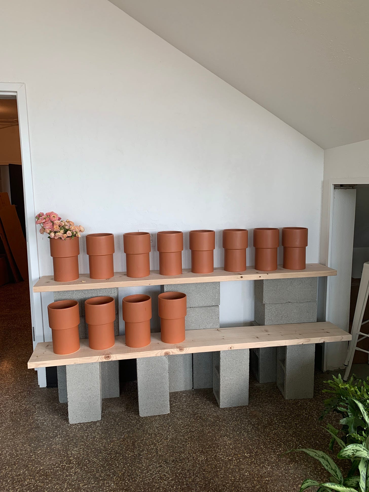 empty terra cotta vases lined up on cinder block and wood shelves