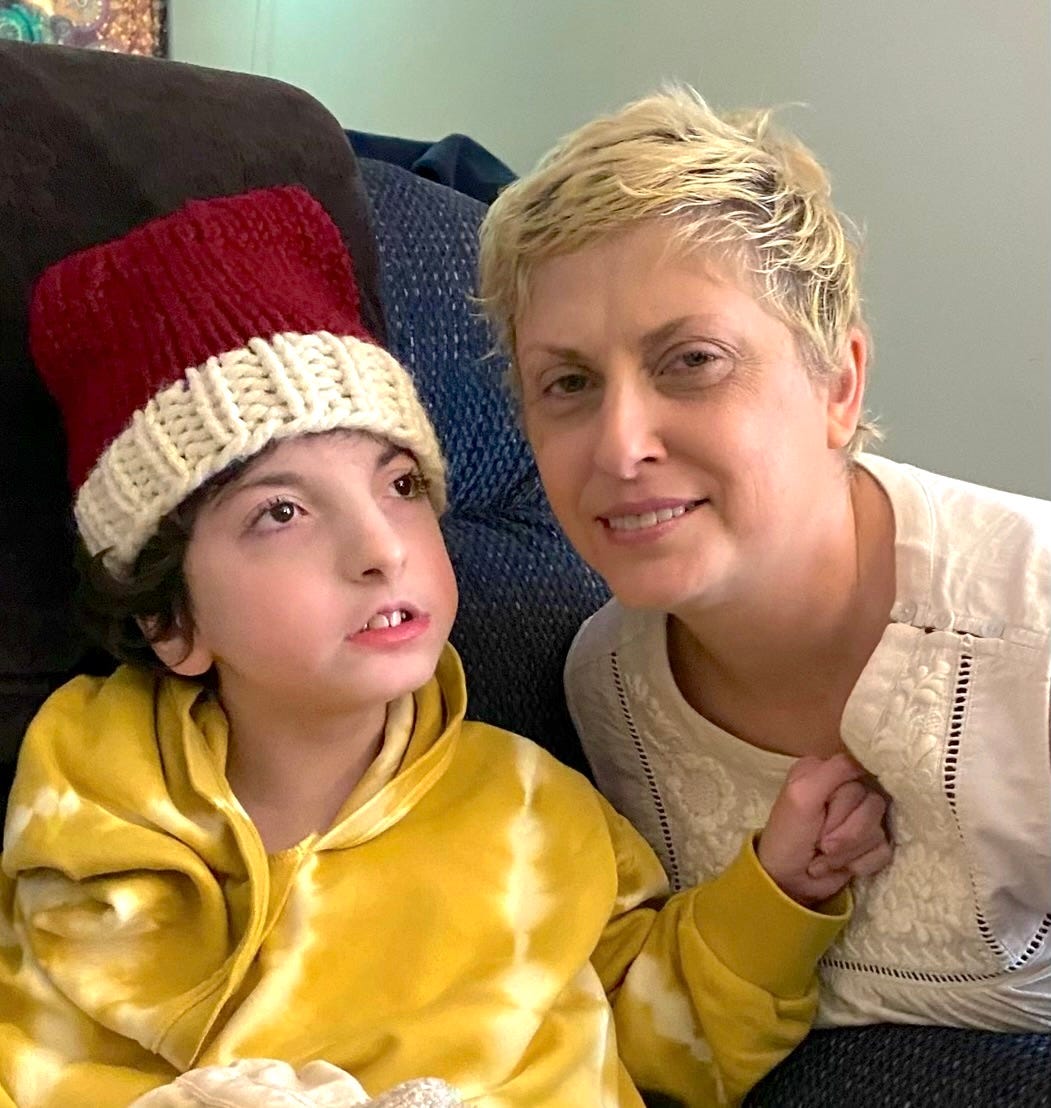 A white mother with short blonde hair and her daughter with dark hair and a red and white knitted cap. 