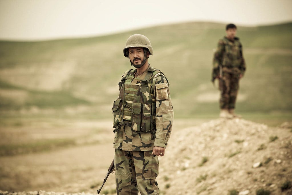 4540561318_c4eff90633_o, Two Afghan soldiers stand watch while a convoy passes in Faryab Province, Afghanistan. The Norwegian Operational Mentor and Liaison Team mentors the 3rd Kandak in Faryab Province, Afghanistan." by ResoluteSupportMedia (ISAF Public Affairs) is licensed under CC BY 2.0, no changes were made.